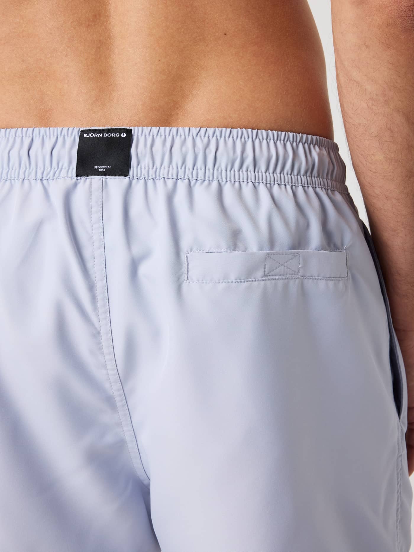 Back view close-up of the Borg Solid Swim Shorts in Icelandic Blue (Blue), showing the logo label and Velcro pocket. - Image 4