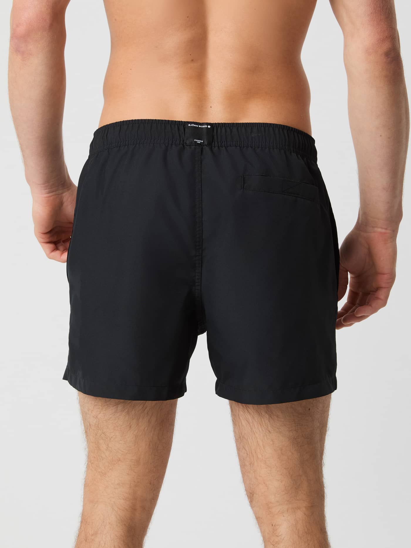 Back view of a man wearing the Borg Solid Swim Shorts in Black Beauty (Black), made from functional recycled polyester. - Image 3