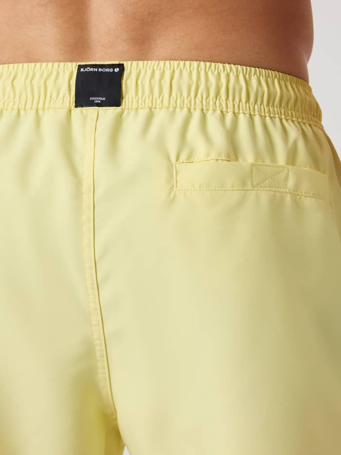 Close-up achteraanzicht van de Borg Solid Swim Shorts in Lemonade (Geel) met een klittenbandzak en zwart logolabel. - Image 4