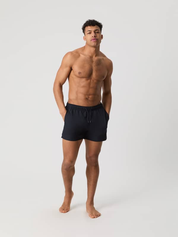 Borg Solid Swim Shorts i Night sky (Marineblå) med løs pasform og sidelommer set forfra i fuld figur på en mand.