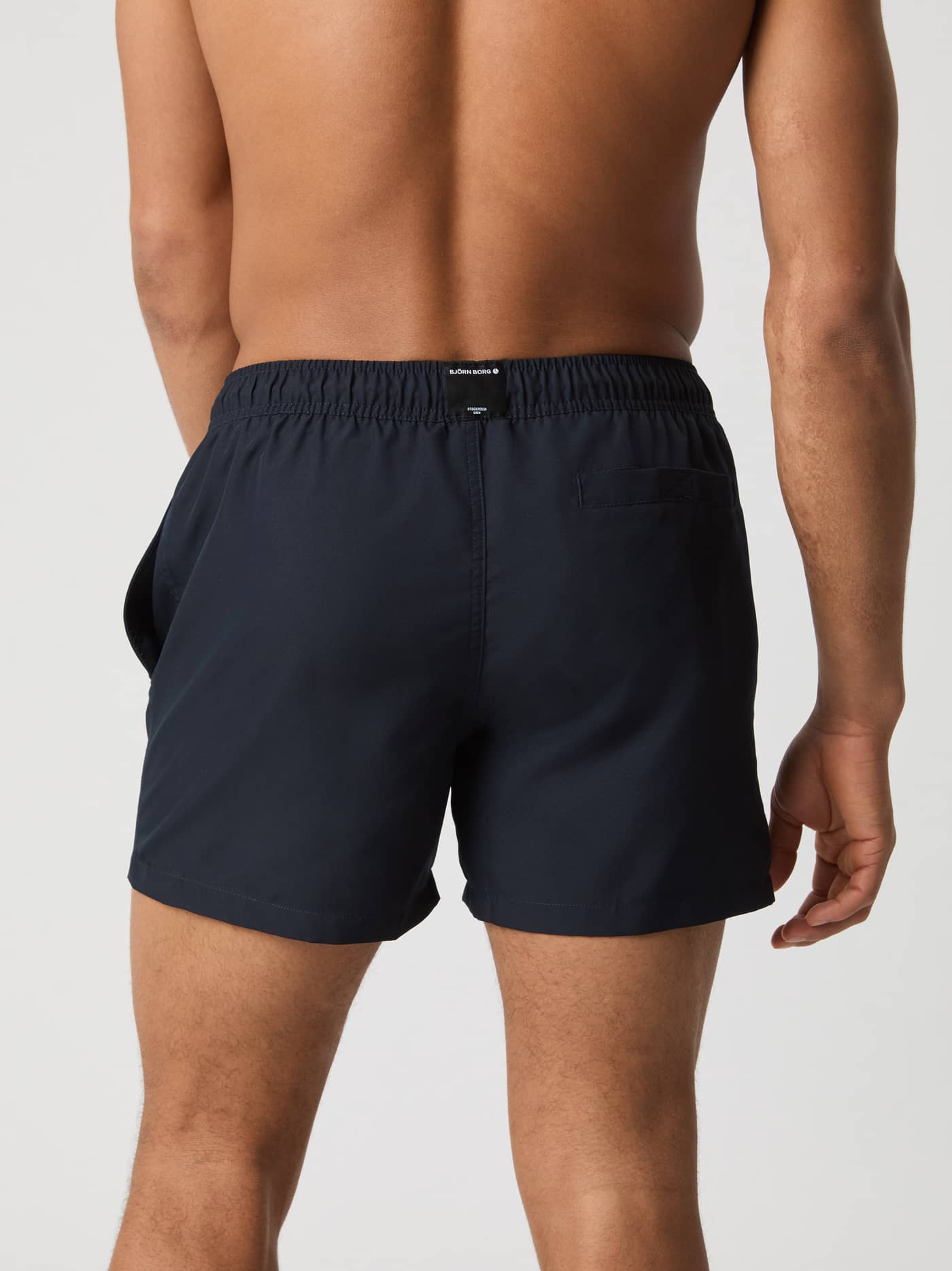 Vue arrière du Borg Solid Swim Shorts en Night Sky (Bleu marine) avec une poche arrière et une étiquette logo. - Image 3