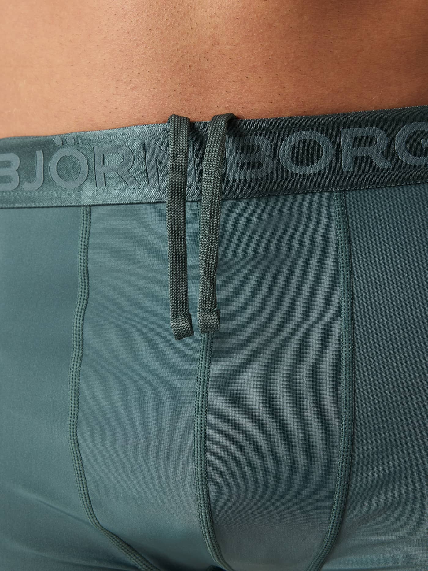 Detail of the Borg Stretch Swim Shorts in Balsam Green (Green), showing the branded waistband and adjustable drawstring. - Image 5