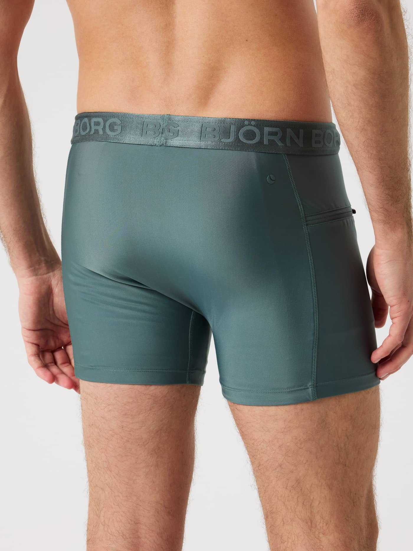 Back view of a man wearing the Björn Borg Stretch Swim Shorts in Balsam Green (Green) with a branded waistband. - Image 3