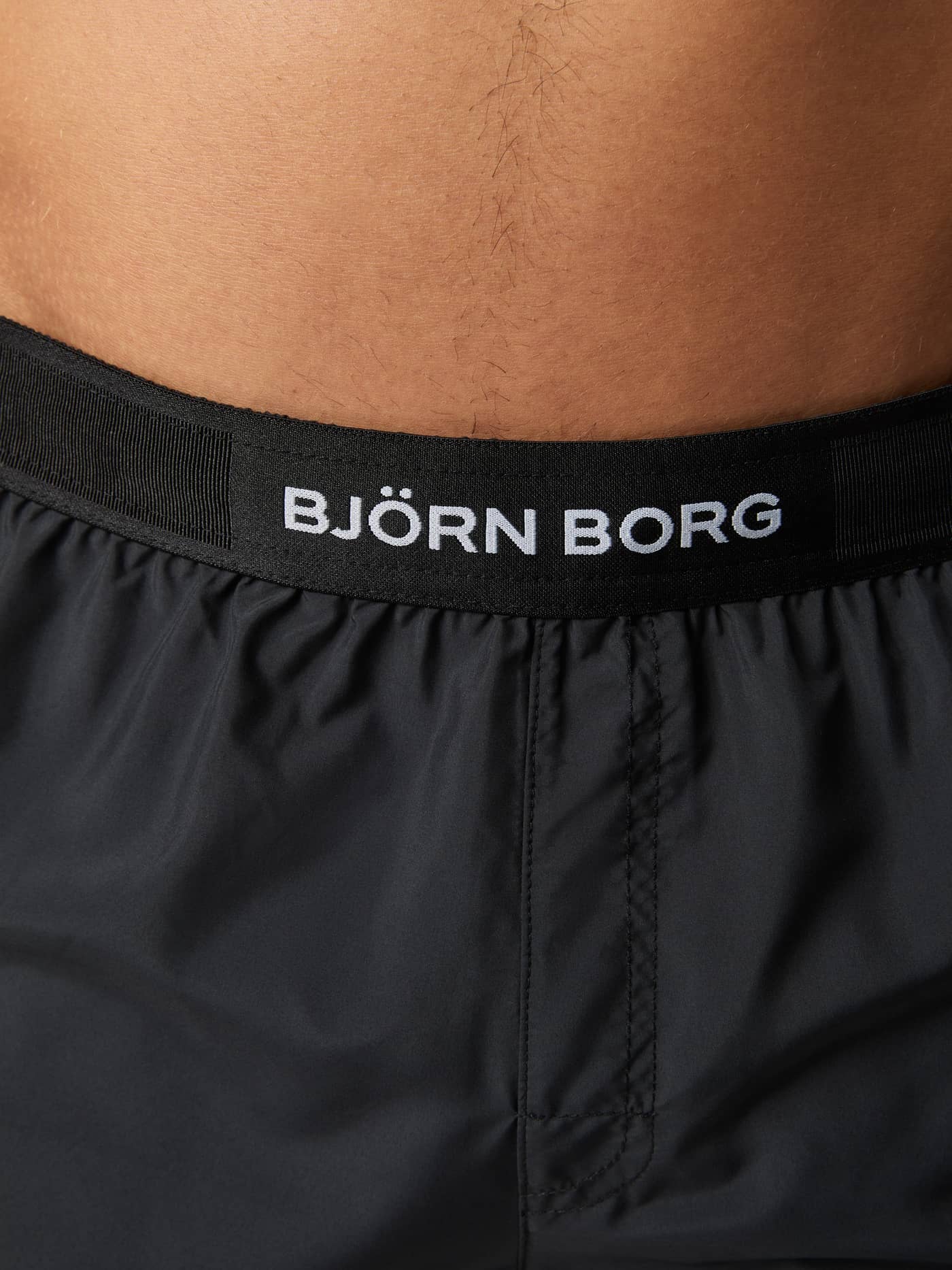 Detailed close-up of the Borg Premium Swim Shorts in Black Beauty (Black), featuring the white logo on the waistband. - Image 5