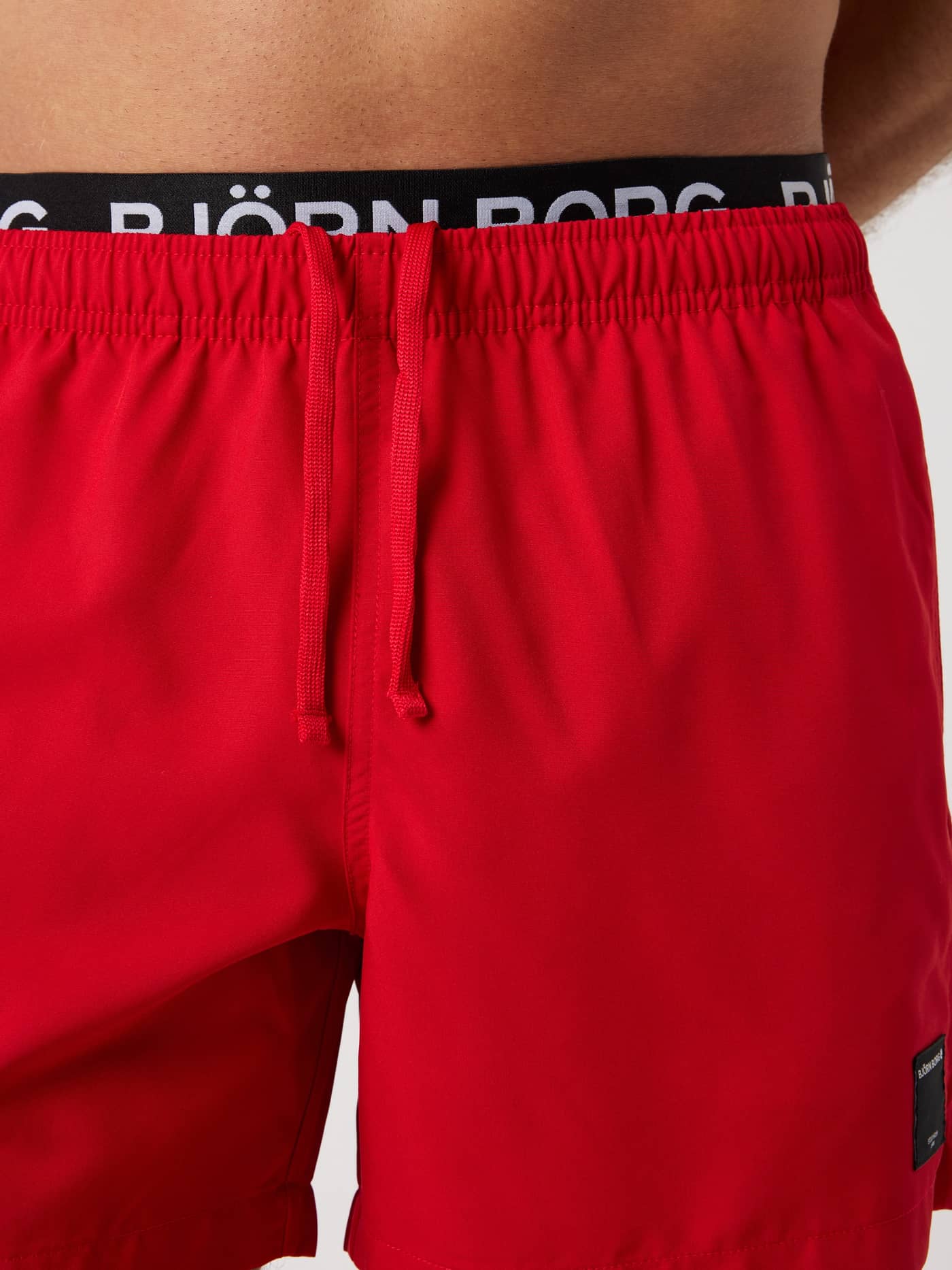 Close-up of the Borg Elastic Swim Shorts in Pompeian Red (Red), showing the white logo elastic waistband and drawstring. - Image 6