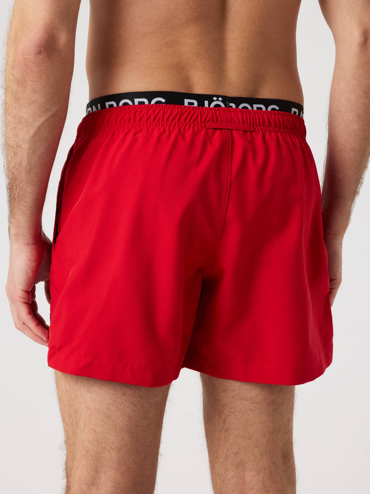 Back view of a man wearing the red Borg Elastic Swim Shorts in recycled polyester, featuring a white logo and a regular fit. - Image 2