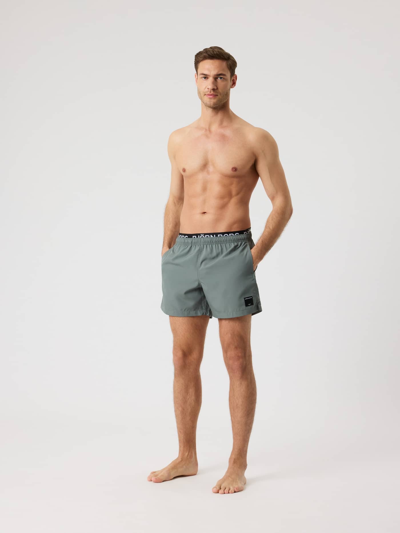 Borg Elastic Swim Shorts i Balsam Green (Grøn) set forfra på en mand med sort og hvidt logobånd. - Image 3