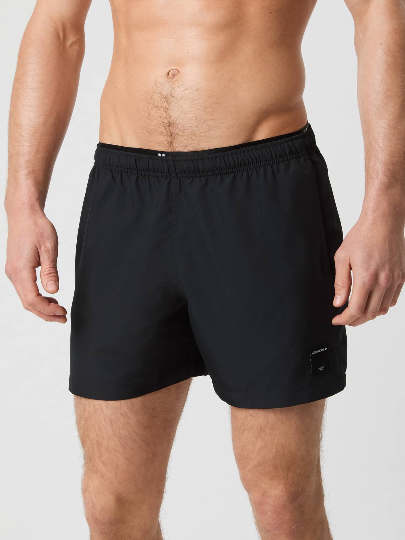 Front view of a man wearing Borg Elastic Swim Shorts in Black Beauty (Black) with a functional, elastic waist and black logo. - Image 2