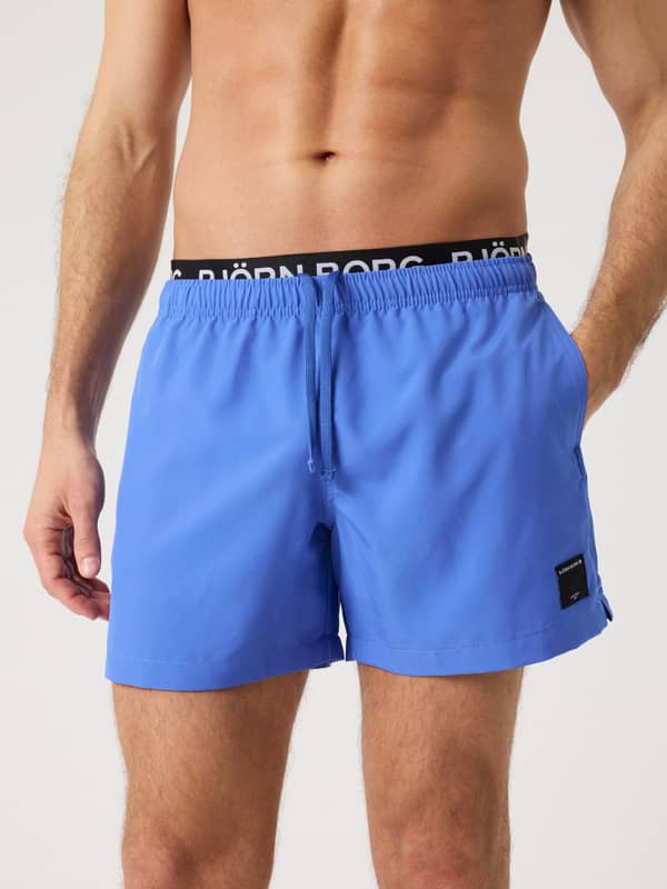 Borg Elastic Swim Shorts i Amparo Blue (Blå) set forfra på en mand med hvidt taljelogo i genanvendt polyester.