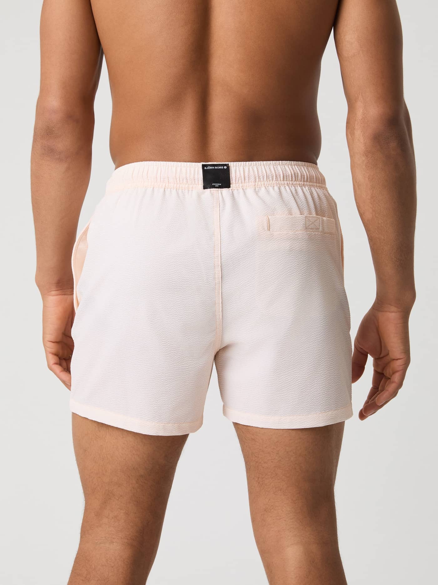 Vista trasera de los Borg Seersucker Swim Shorts en Swim Stripe 3 (Rosa) con logotipo negro y bolsillo funcional. - Image 3