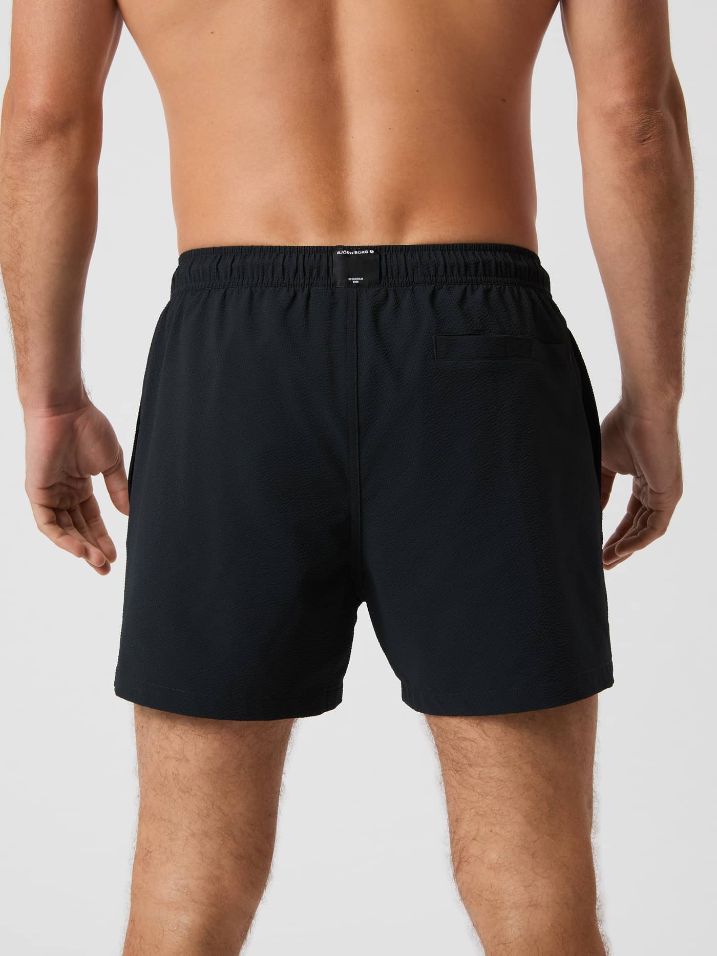 Borg Seersucker Swim Shorts in Black Beauty (Zwart) met seersucker-textuur en wit logo op een man in achteraanzicht. - Image 3