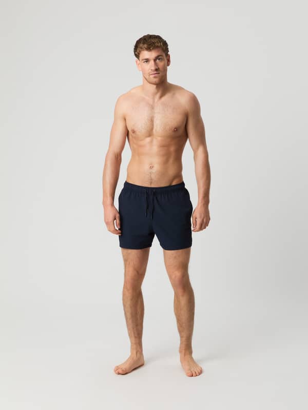 Borg Seersucker Swim Shorts i Night Sky (Marineblå) set forfra i fuld figur på en mand i stribet seersuckerstof.
