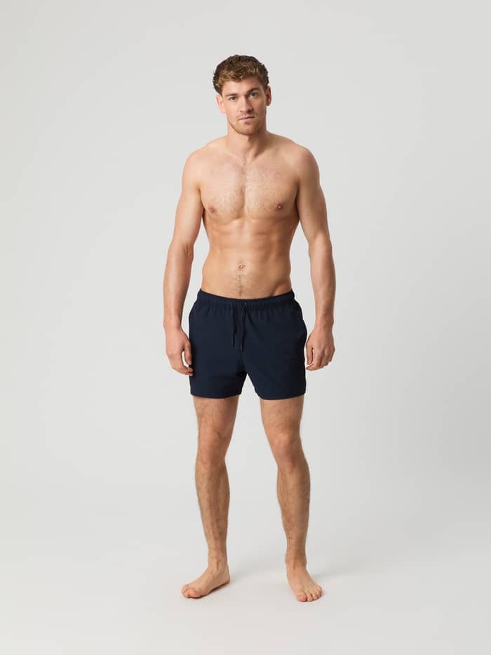 Borg Seersucker Swim Shorts i Night Sky (Marineblå) set forfra i fuld figur på en mand i stribet seersuckerstof.
