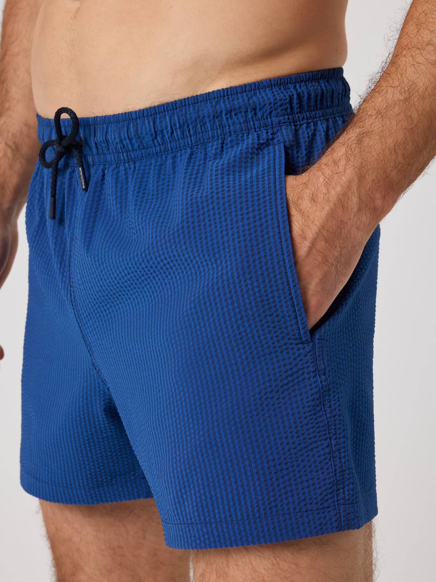 Primer plano de los Borg Seersucker Swim Shorts en Searstripe 4 (Azul) con tejido seersucker de rayas y bolsillo lateral. - Image 4