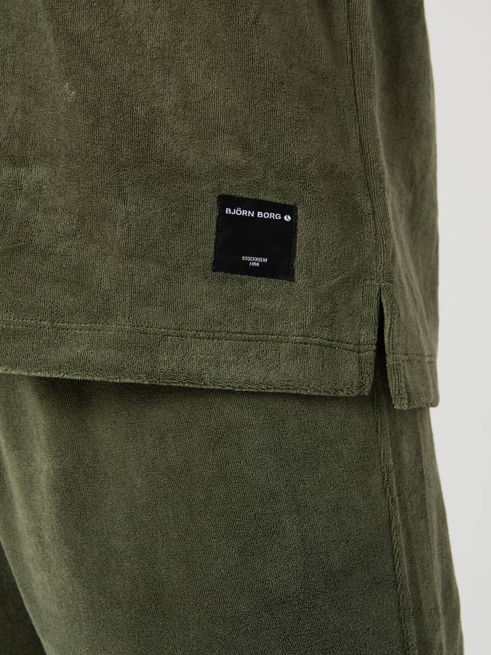 Nahaufnahme des Borg Toweling Pool Shirt in Beetle (Grün) aus Frottee mit schwarzem gewebtem Logo-Label. - Image 5