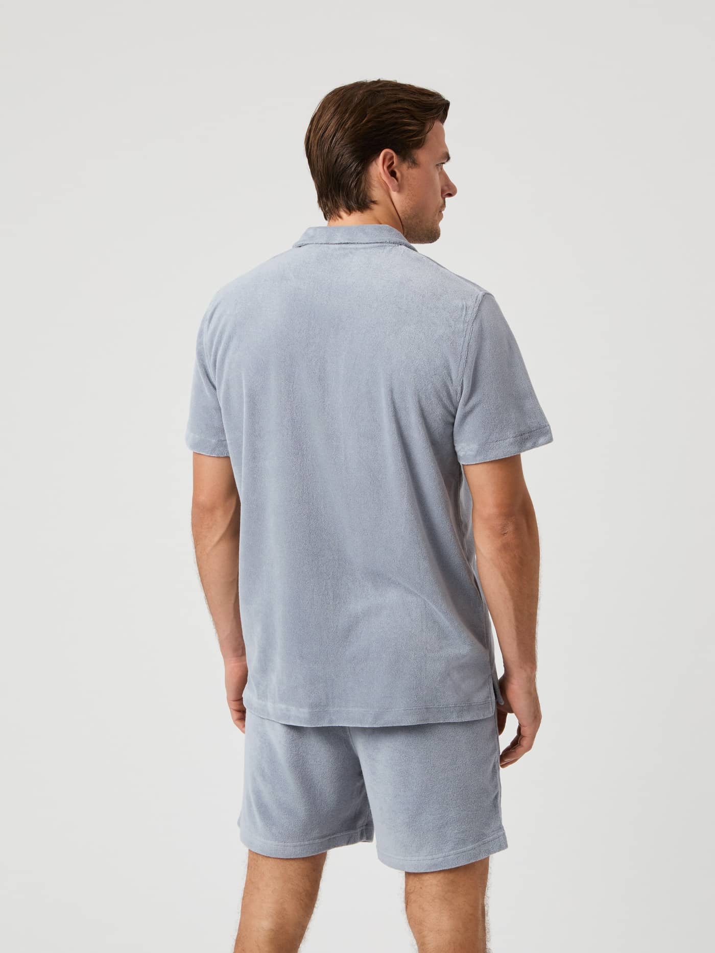 Back view of a man wearing the Borg Toweling Pool Shirt in Tradewinds (Grey) made of soft toweling fabric. - Image 2