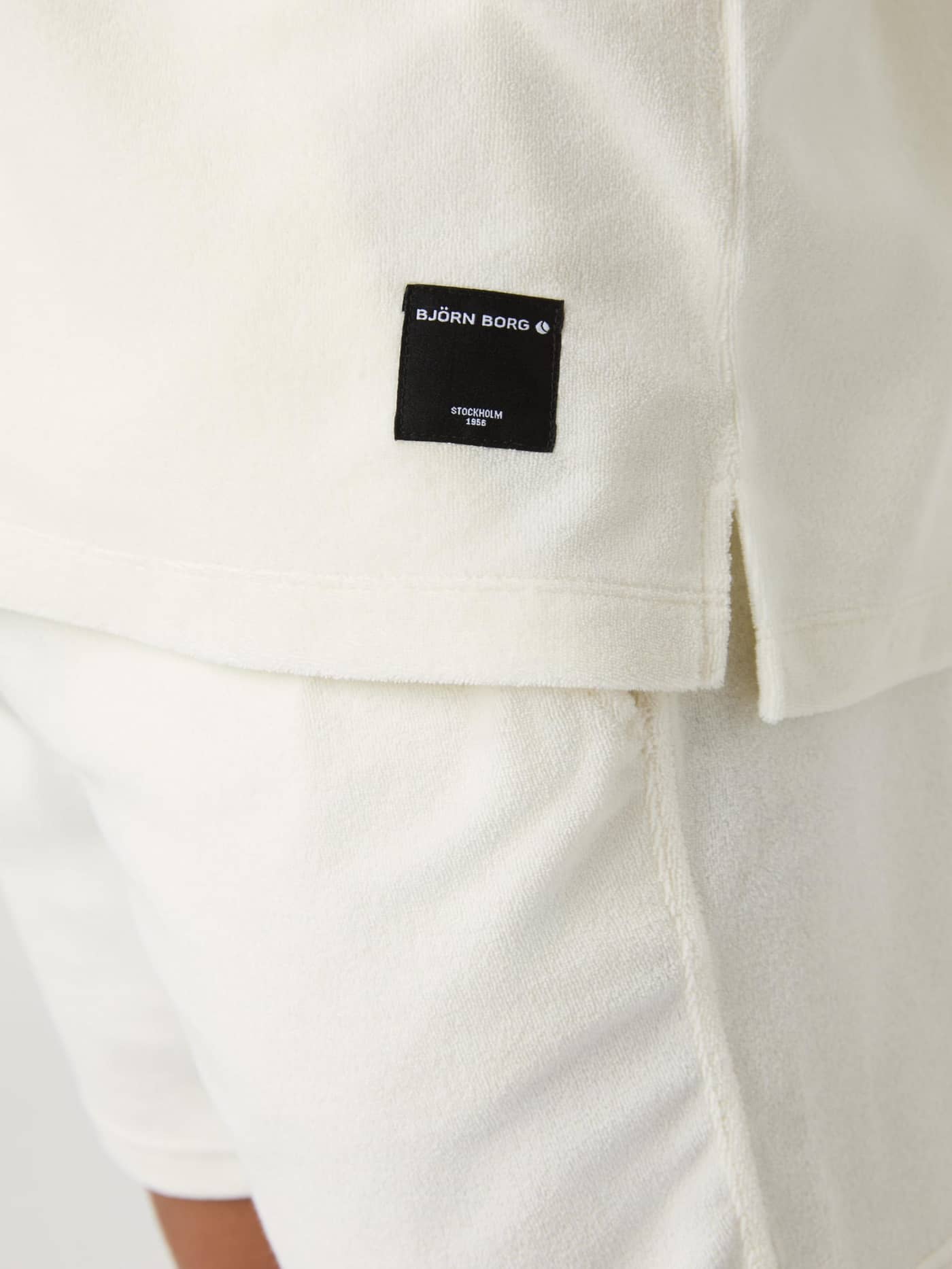 Nahaufnahme des Borg Toweling Pool Shirt in Egret (Weiß) aus weichem Frotteestoff mit schwarzem Logo-Label. - Image 4