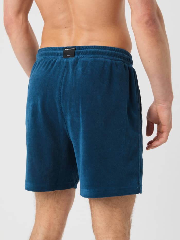Achteraanzicht van een man in de Borg Toweling Pool Shorts in Gibraltar Sea (Blauw) met een zwart logo op de tailleband. - Image 3