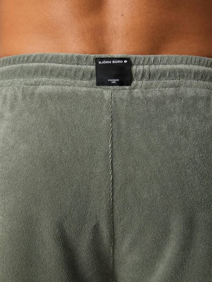 Close-up van het zwarte logolabel op de tailleband van de Borg Toweling Pool Shorts in Agave Green (Groen) van badstof. - Image 4