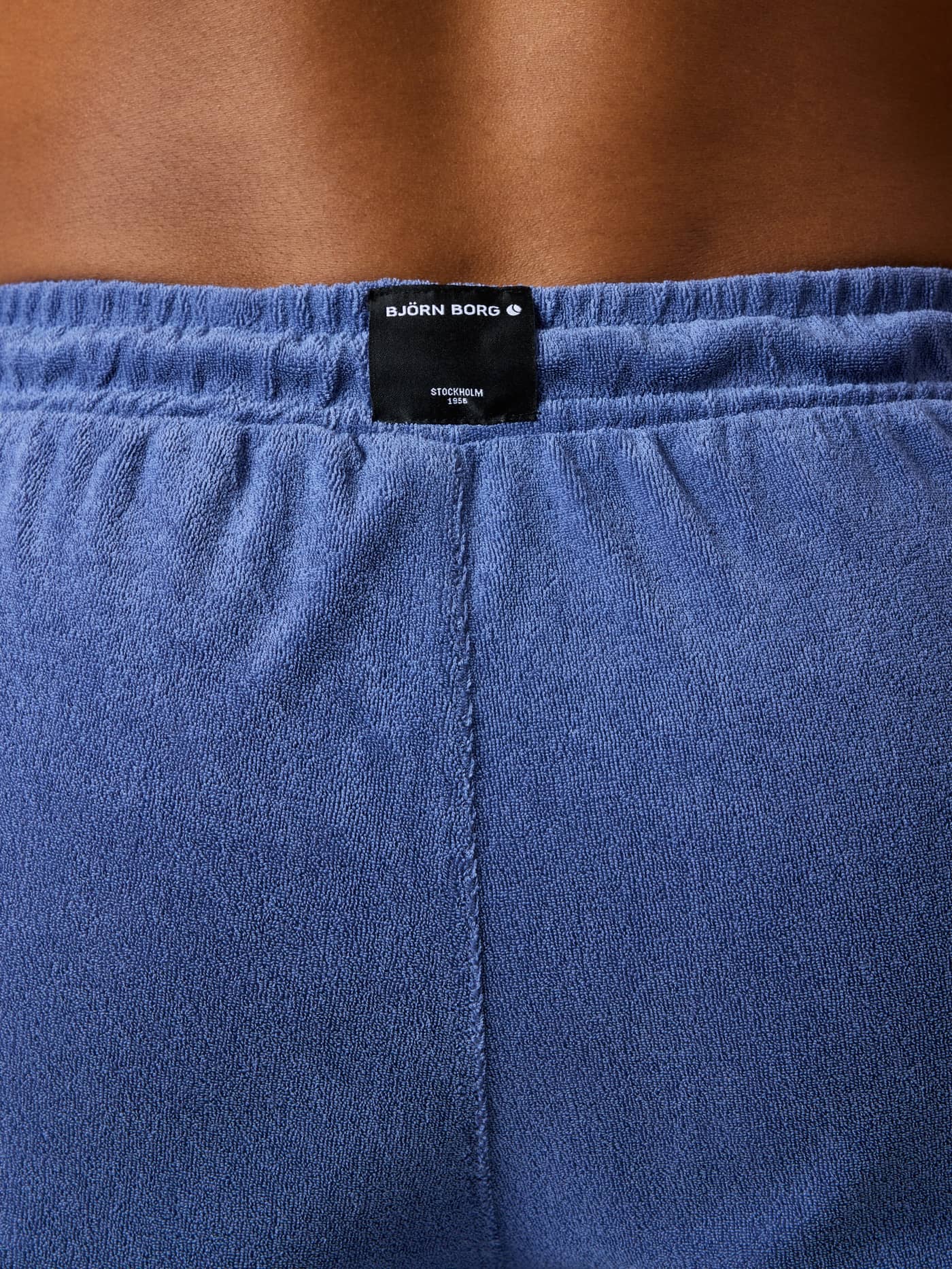 Detailed back view of the Borg Toweling Pool Shorts in Coastal Fjord (Blue) with a black logo and toweling fabric. - Image 2