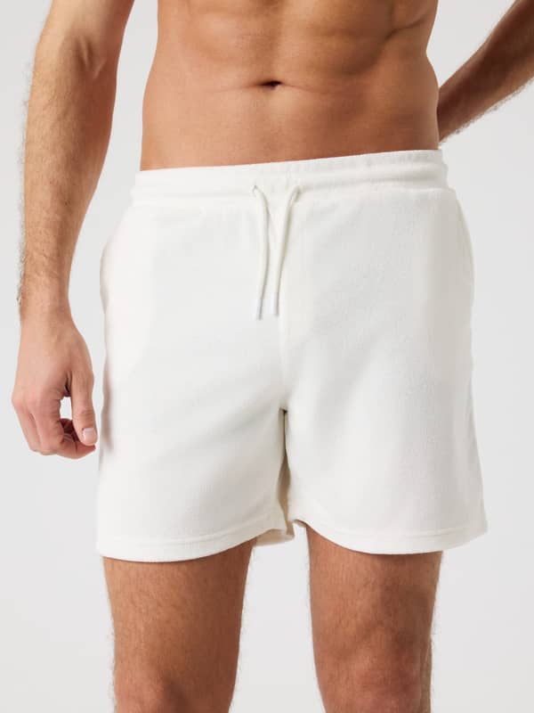 Vue de face d'un homme portant le Borg Toweling Pool Shorts en Tofu (Blanc) en tissu éponge avec une coupe régulière.