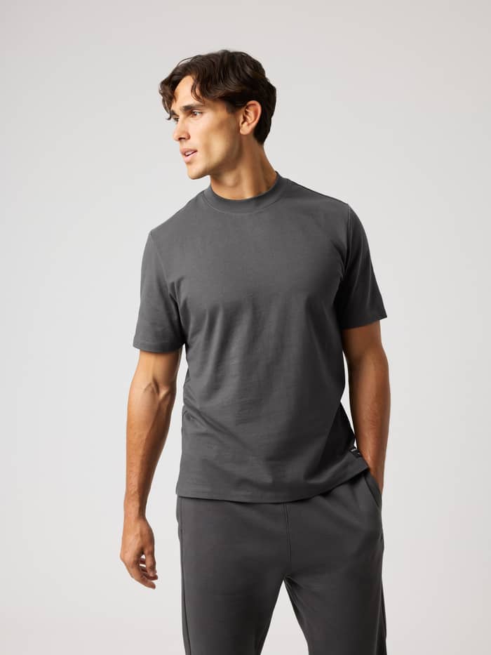 Front view of a man wearing the cotton Centre High Neck T-Shirt in Asphalt (Grey) with a relaxed, oversized fit.