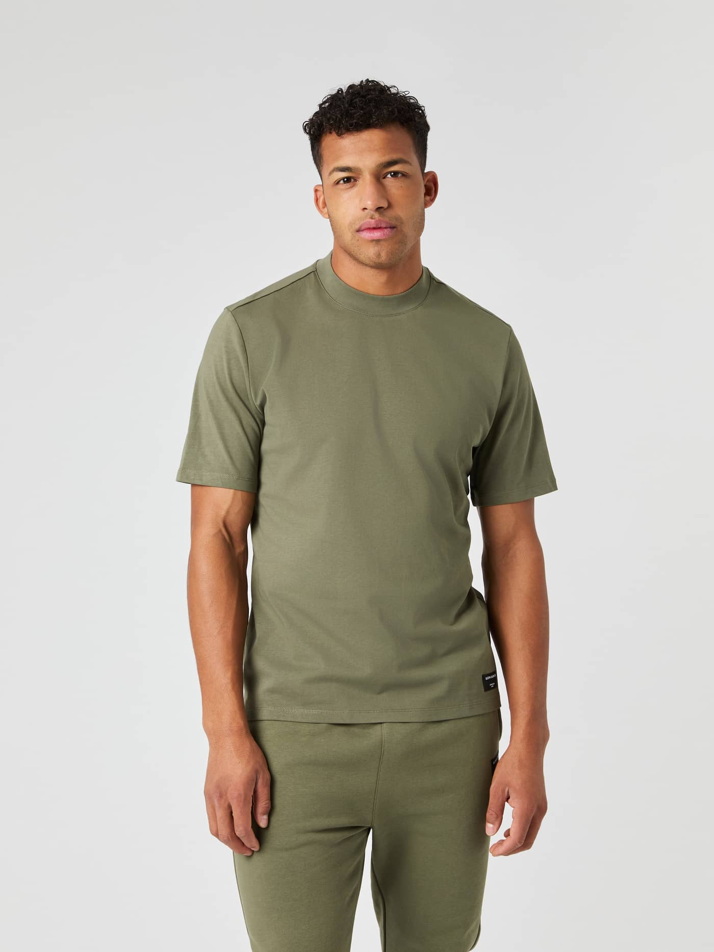 Front view of a man in the oversized Björn Borg Centre High Neck T-Shirt in cotton Dusty Olive (Green) with a black logo. - Image 2