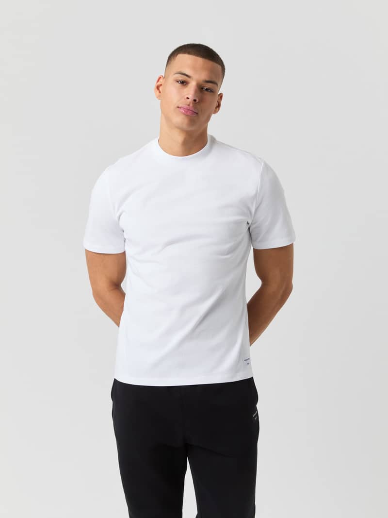 Front view of a man wearing the Björn Borg Centre High Neck T-Shirt in Brilliant White (White) with an oversized fit.