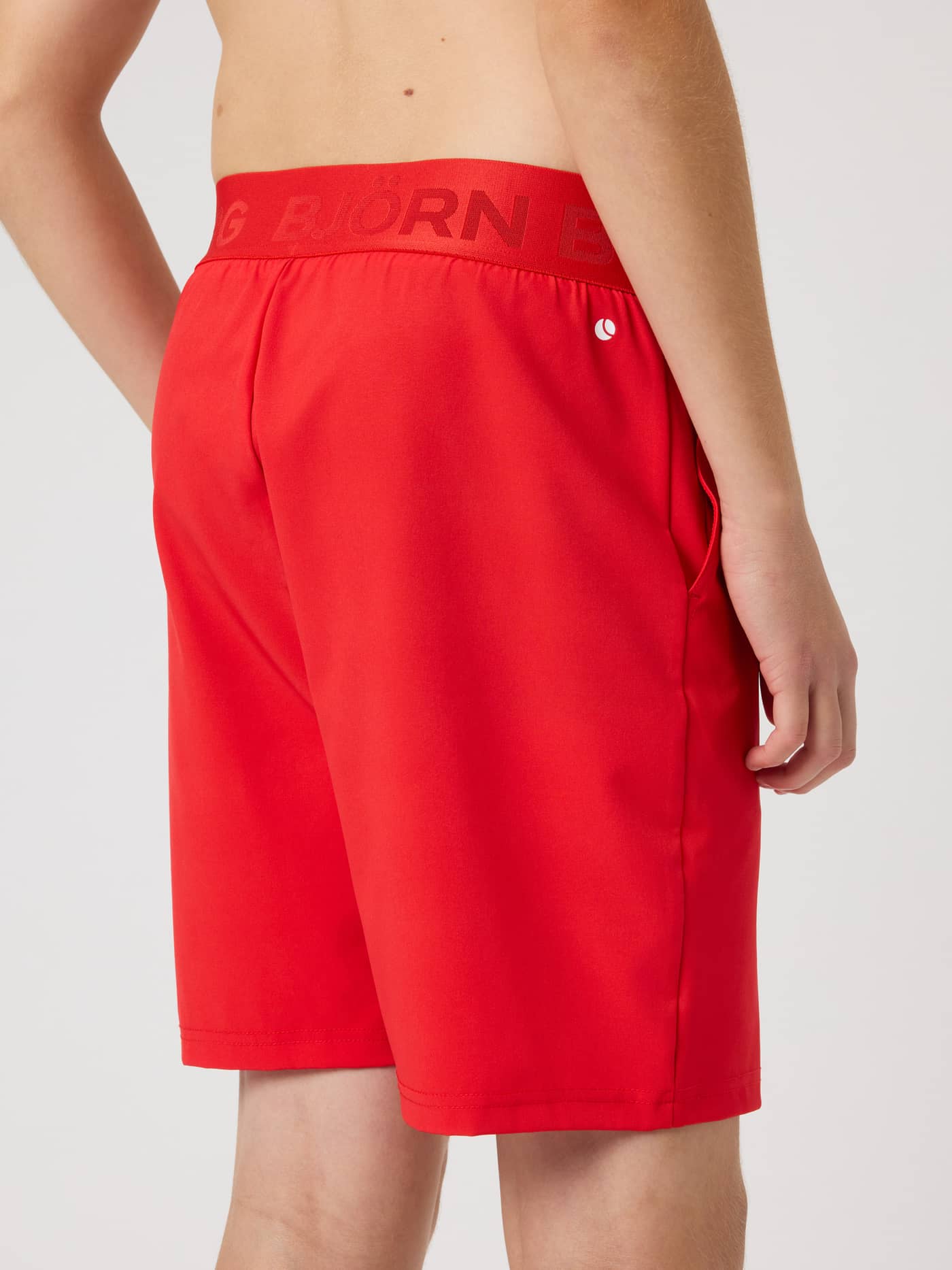 Side view of kids' Borg Shorts in Flame Scarlet (Red) for training with a branded waistband and white logo. - Image 3