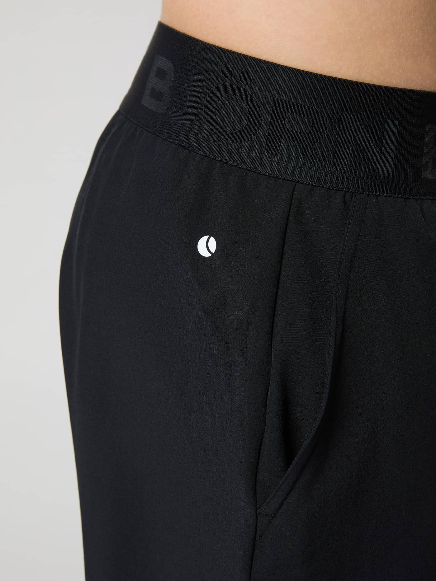 Närbild på Borg Shorts för barn i Black Beauty (Svart) för träning med elastisk märkesresår och vit logotyp. - Image 4