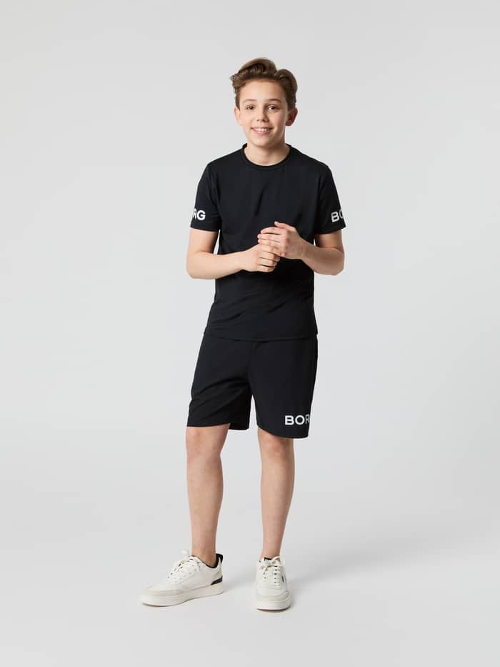 Full-body front view of a model wearing the Björn Borg Shorts in Black Beauty (Black) with a white logo for kids training.
