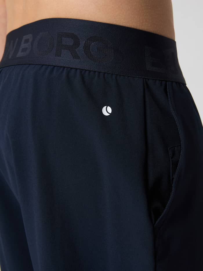 Nahaufnahme der Borg Shorts für Kinder in Night sky (Marineblau) mit elastischem Markenbund und weißem Logo für das Training. - Image 4