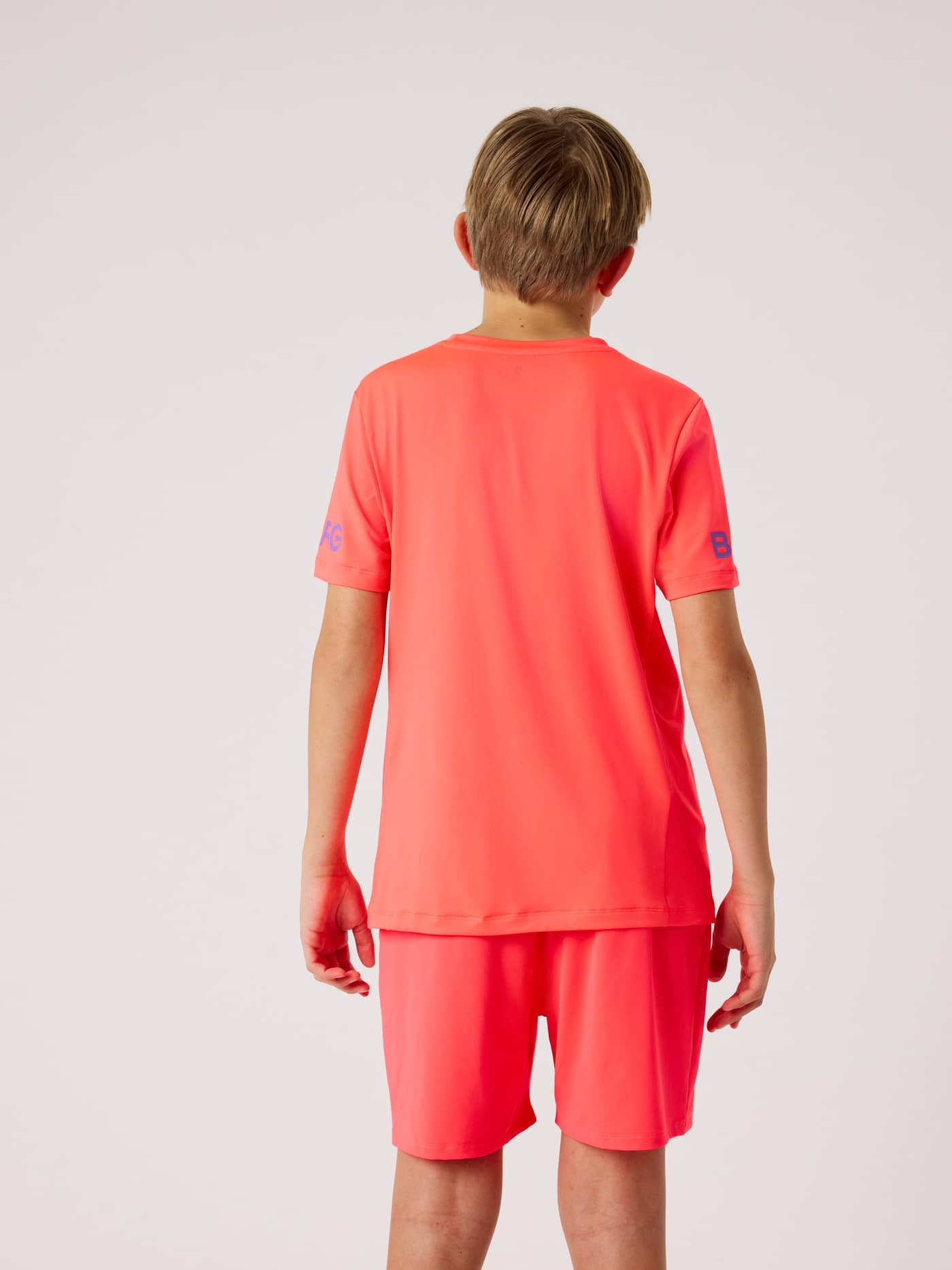 Bakifrån på ett barn i Borg T-Shirt i Diva Pink (Rosa) för träning med blå logotyper på ärmarna. - Image 3