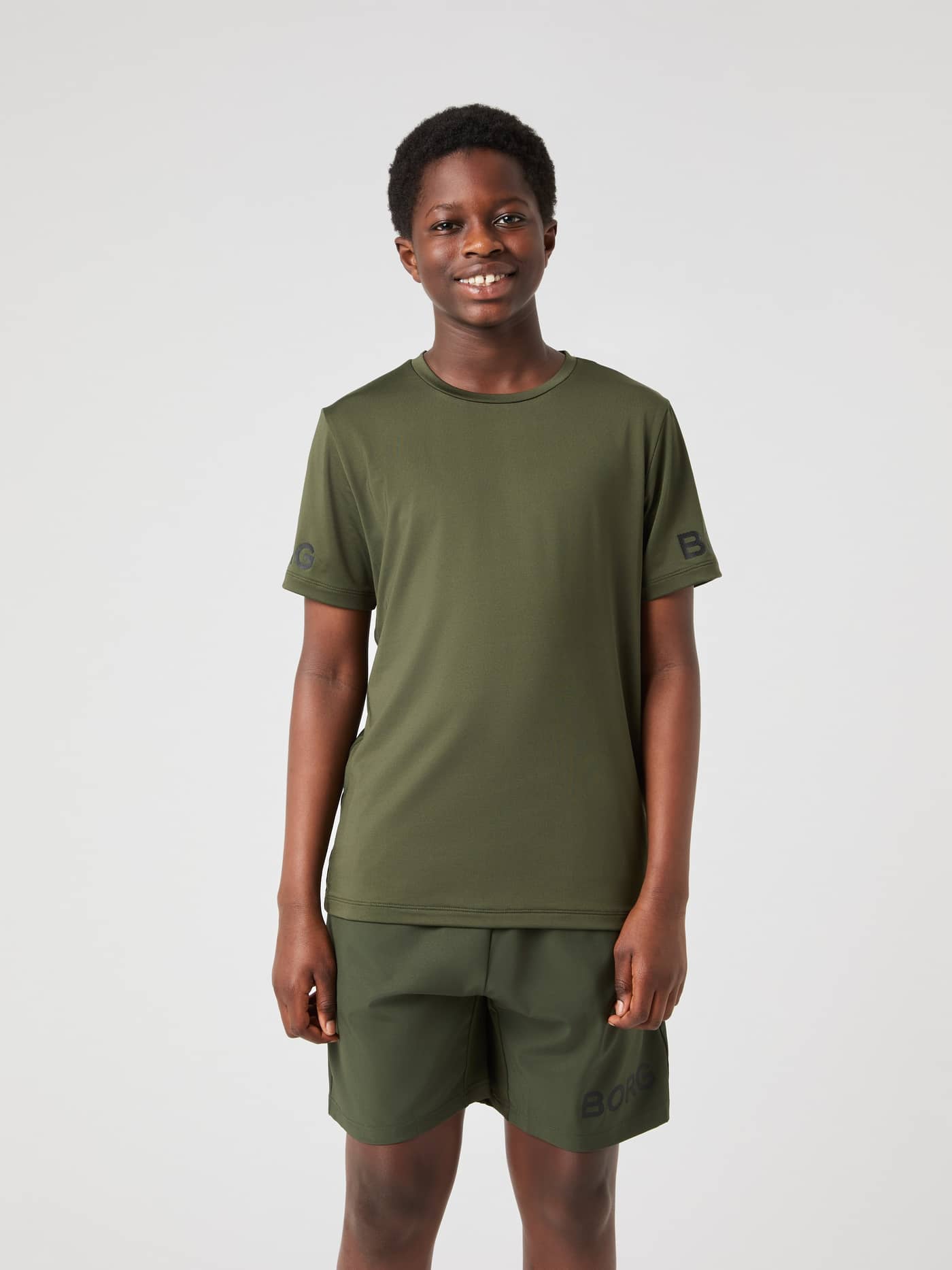 Front view of a kid wearing the Björn Borg T-Shirt in Forest Night (Green) with black sleeve logos for training. - Image 1