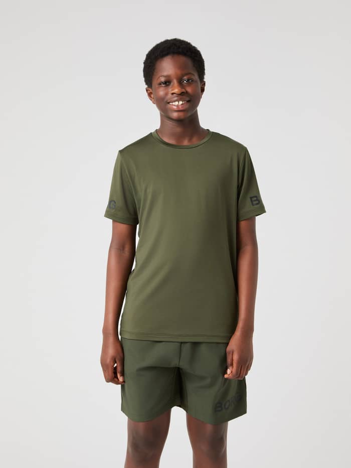 Front view of a kid wearing the Björn Borg T-Shirt in Forest Night (Green) with black sleeve logos for training.