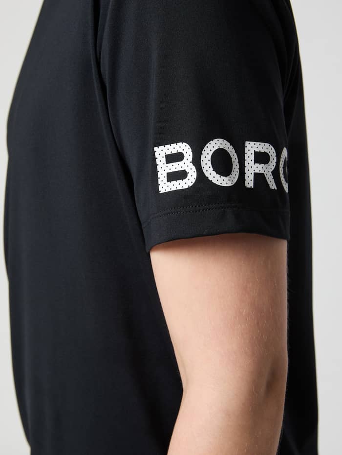 Nahaufnahme des weiß gepunkteten Logos am Ärmel des Borg T-Shirts für Kinder in Black Beauty (Schwarz) für das Training. - Image 4