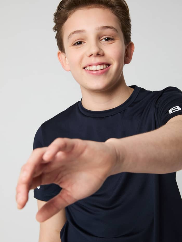 Front view of a smiling boy in the Night sky (Navy) Borg T-shirt for kids, a training top with a white sleeve logo.
