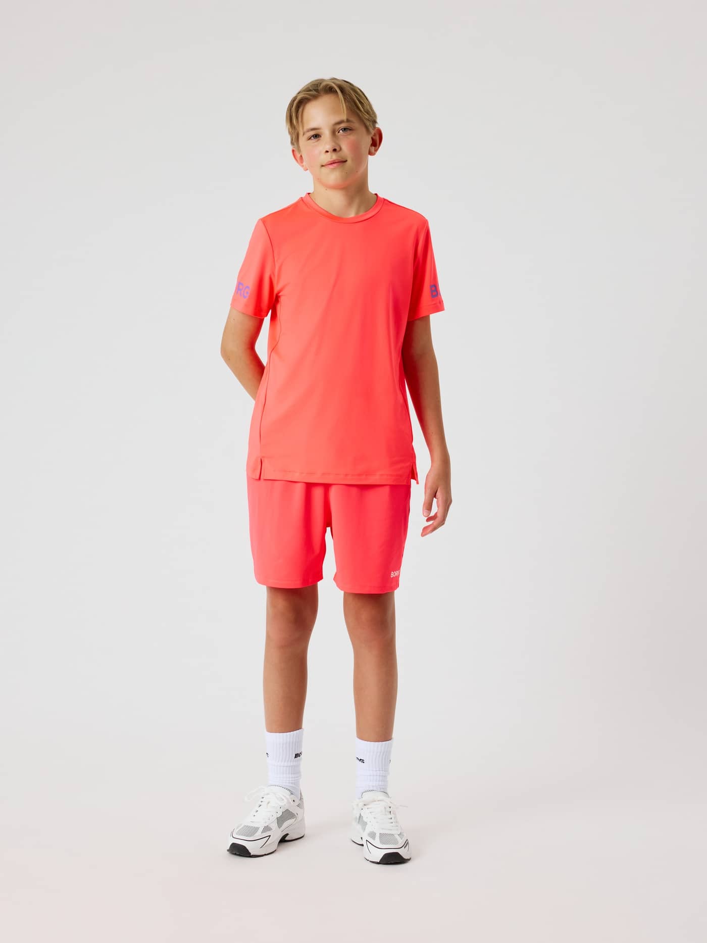 Barn i helfigur framifrån i Borg T-Shirt och shorts i Diva Pink (Rosa) med blå logotyper för träning. - Image 2
