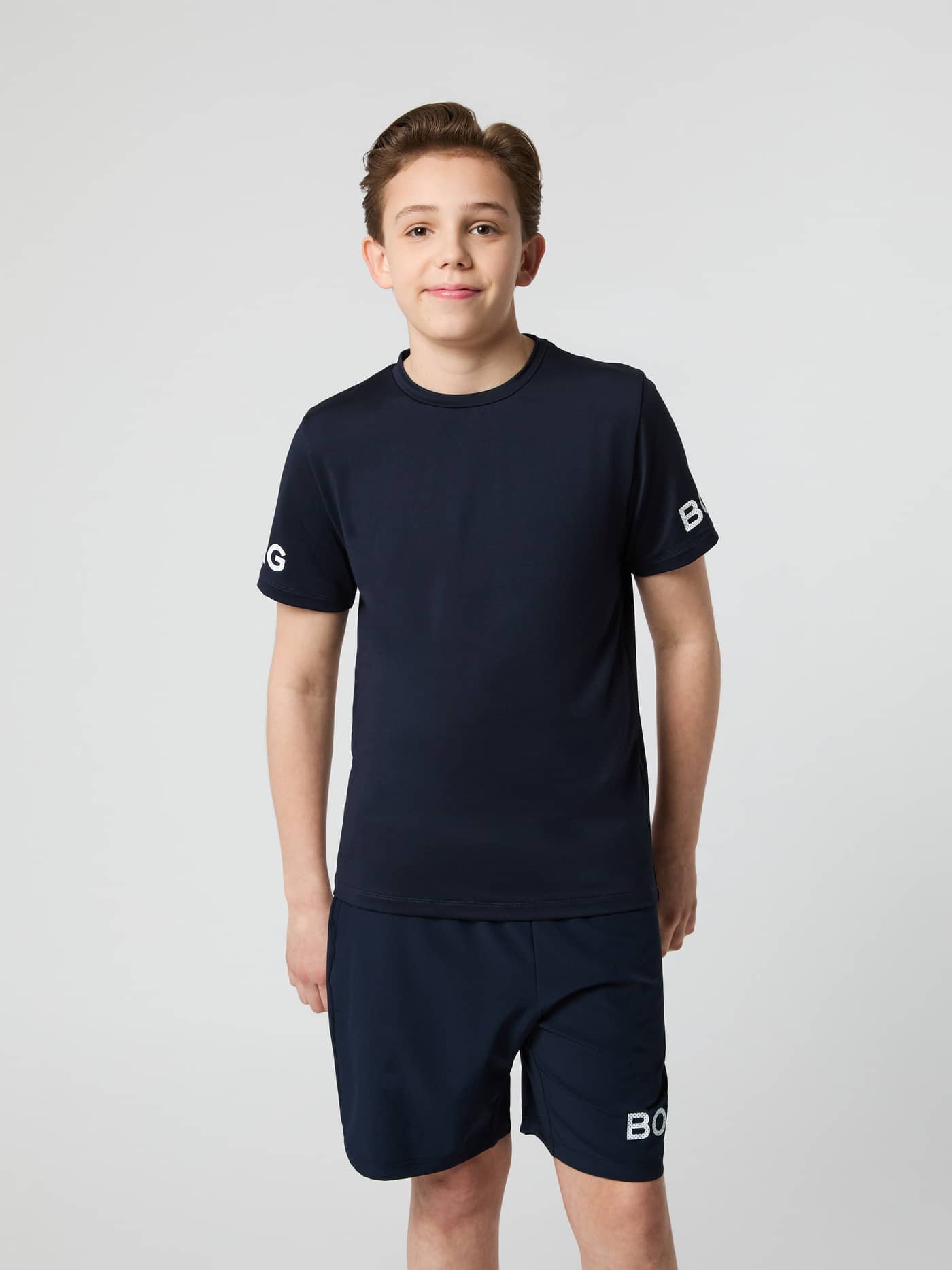 Vue de face d'un enfant portant le Borg T-Shirt Night Sky (Marine) pour l'entraînement, avec logos sur les manches. - Image 2