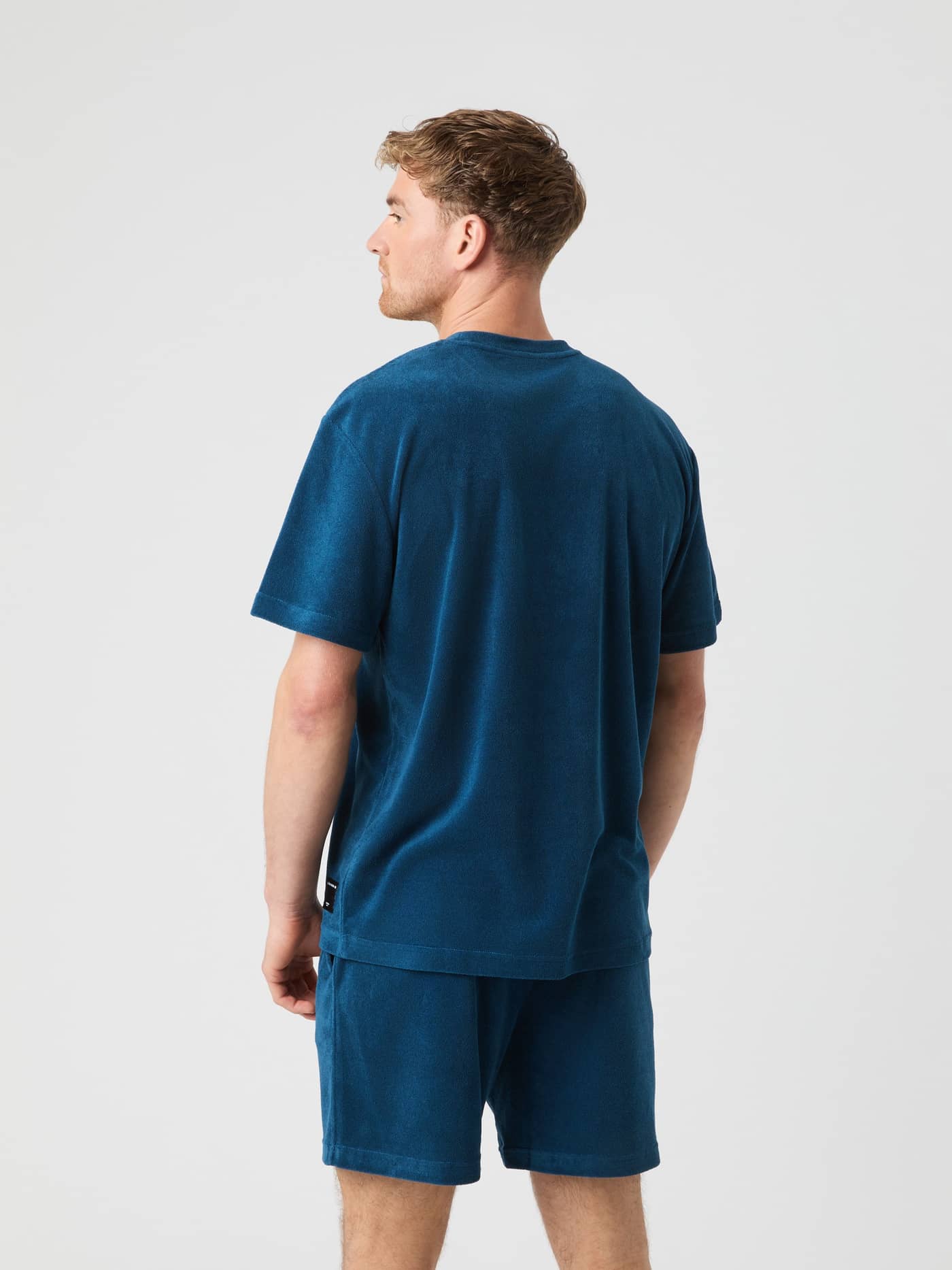 Back view of a model wearing the Borg Toweling T-Shirt in Gibraltar Sea (Blue), crafted from soft cotton toweling fabric. - Image 2