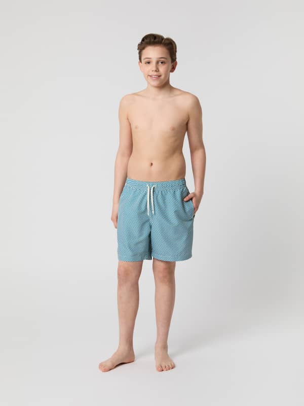 Borg Print Swim Shorts til børn i Candy Stripe 2 (Blå) set forfra på en dreng i et stribet, hurtigtørrende materiale.
