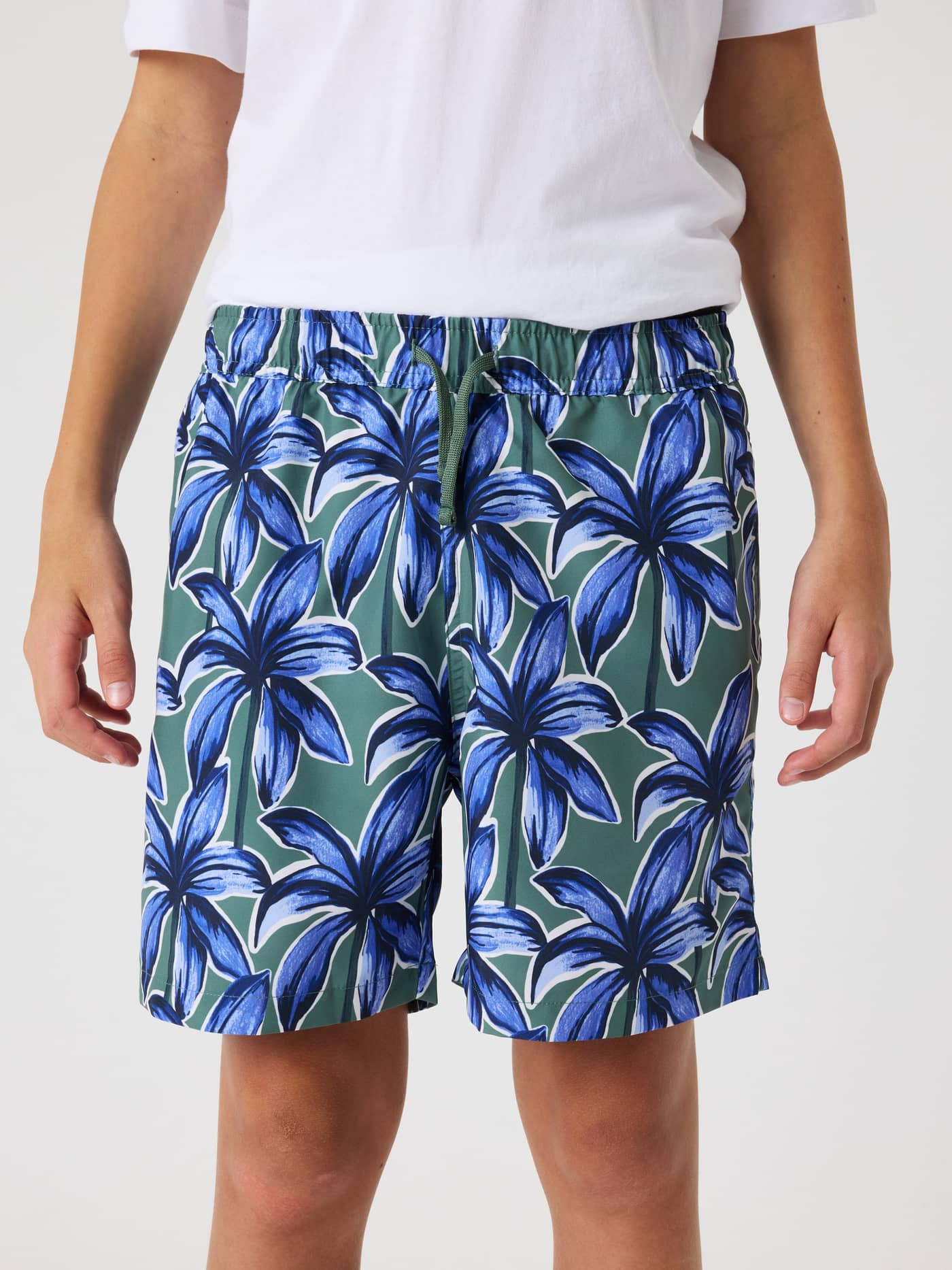 Front view of kids wearing regular-fit Borg Print Swim Shorts in Palms On Palms 1 (blue and green) with a palm tree print. - Image 2