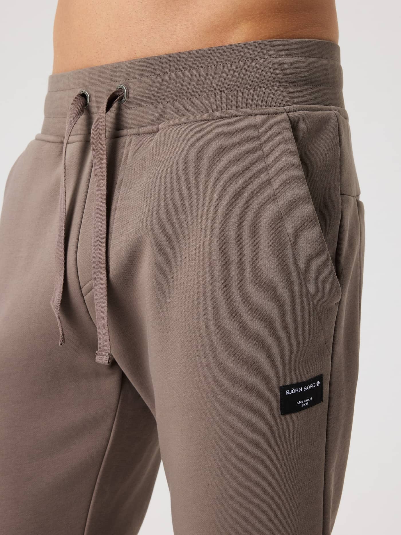 Close-up of the Centre Tapered Sweatpants in Falcon (Brown) featuring the drawstring waist and a black logo label. - Image 4