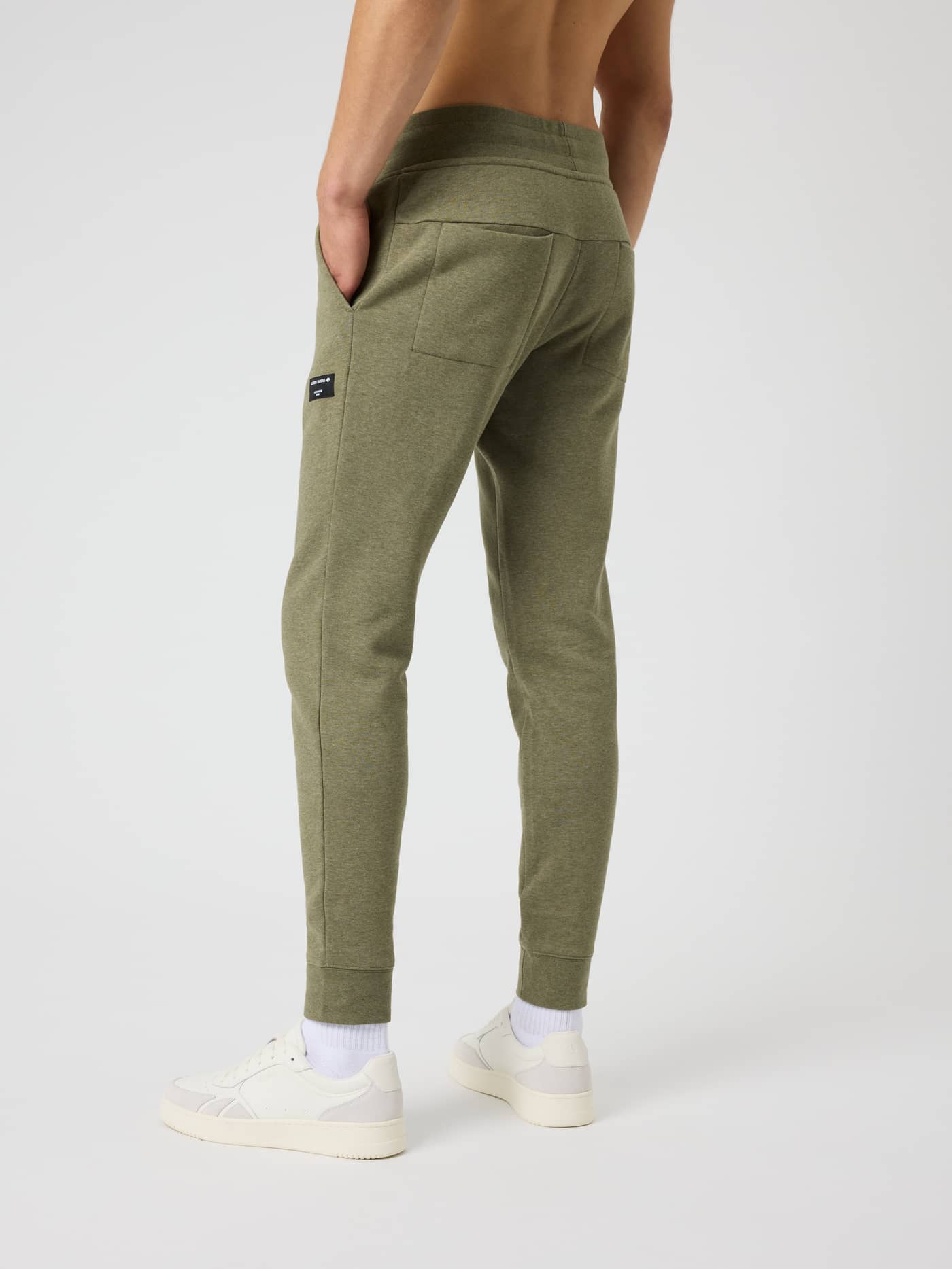 Back view of a man in Björn Borg Centre Tapered Sweatpants in Winter Moss Melange (Green) with a melange pattern and logo. - Image 2