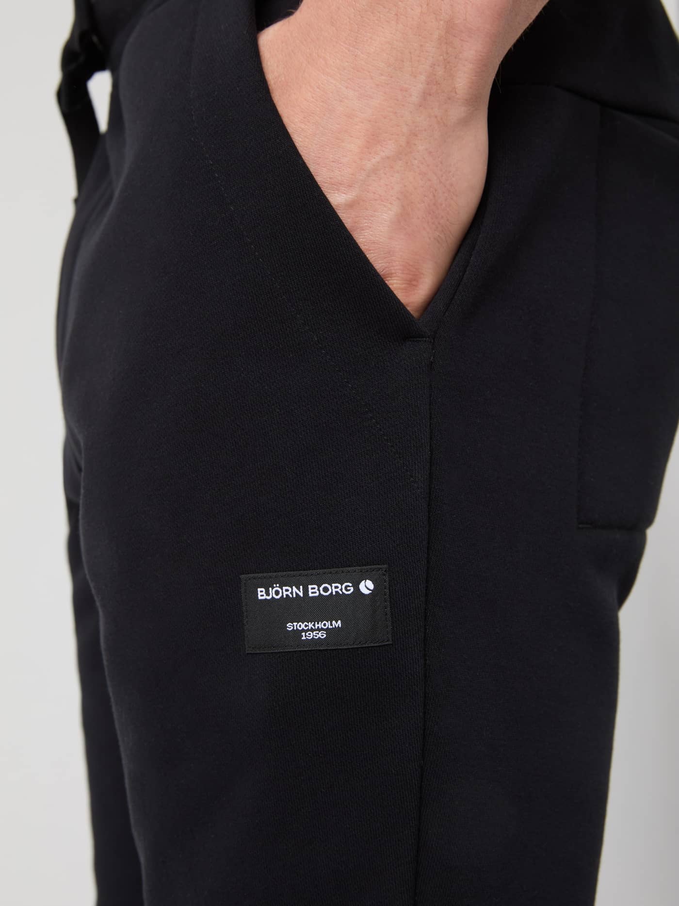 Close-up of the side pocket and Björn Borg logo label on the black Centre Tapered Sweatpants for men. - Image 4