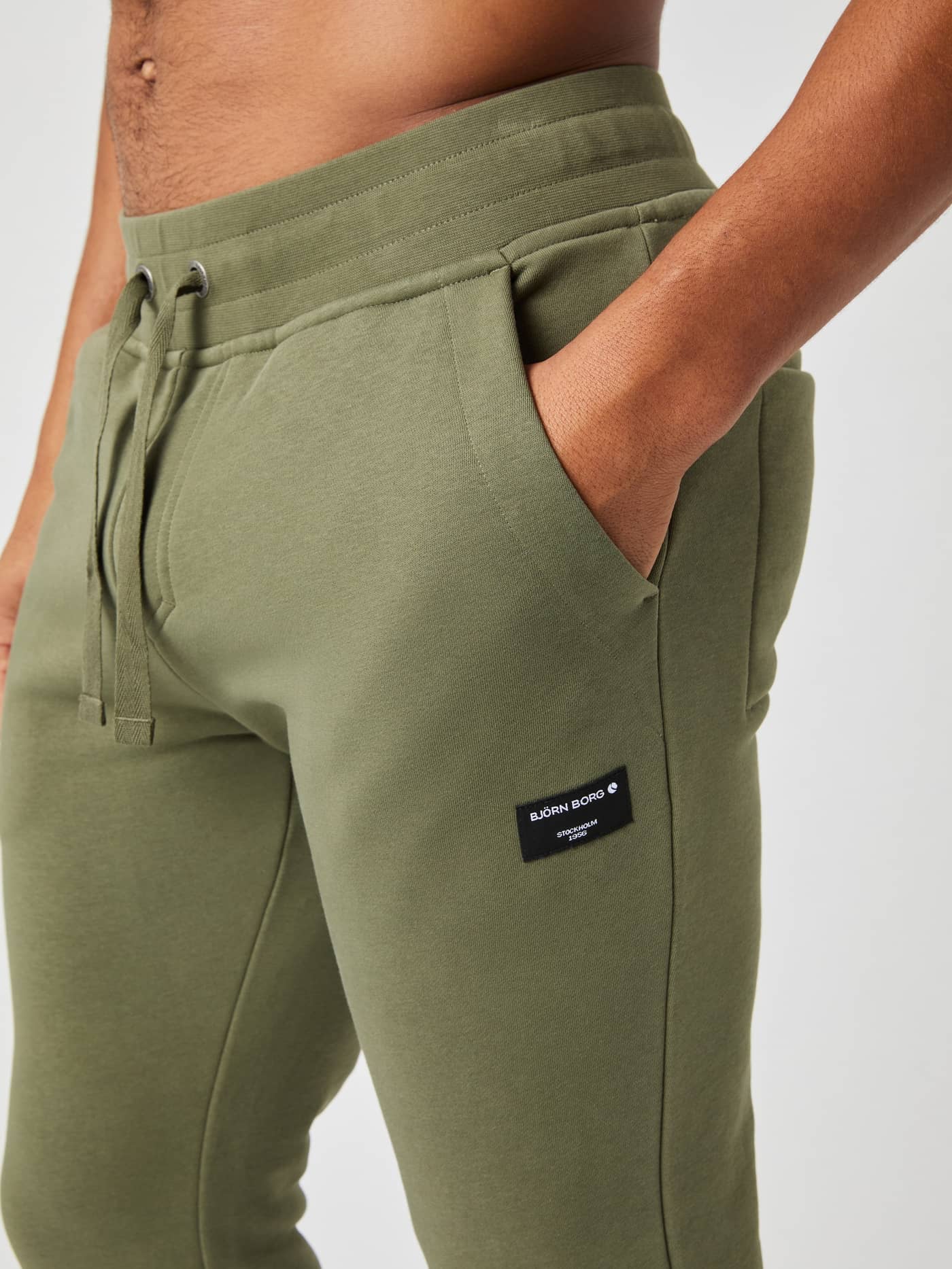 Centre Tapered Sweatpants i Dusty Olive (Grøn) set i nærbillede med fokus på talje, lomme og det sorte logomærke. - Image 3