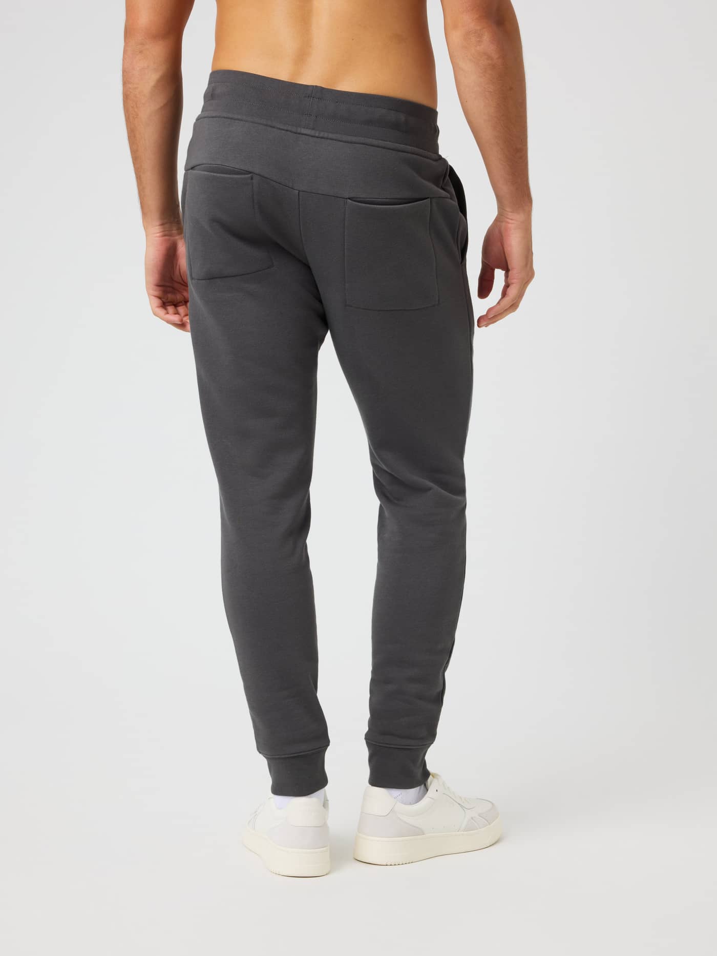 Back view of a man wearing Björn Borg Centre Tapered Sweatpants in Asphalt (Grey) with a slim fit and back pockets. - Image 2