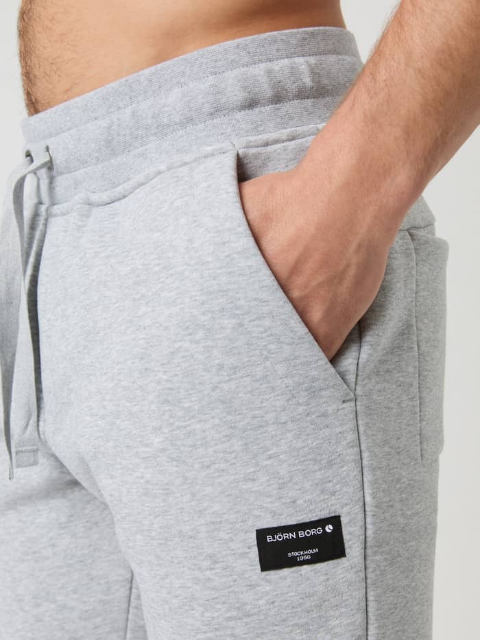 Close-up van de Centre Tapered Sweatpants in Light Grey Melange (Grijs) met zijzak, tailleband en zwart Björn Borg-logo. - Image 4
