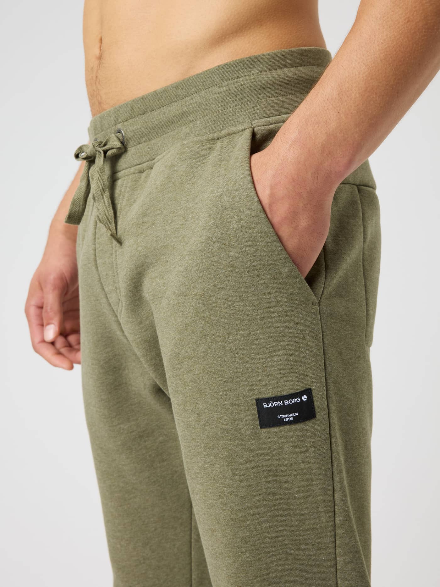 Close-up of the Björn Borg Centre Tapered Sweatpants in Winter Moss Melange (Green) with a side pocket and black logo. - Image 4