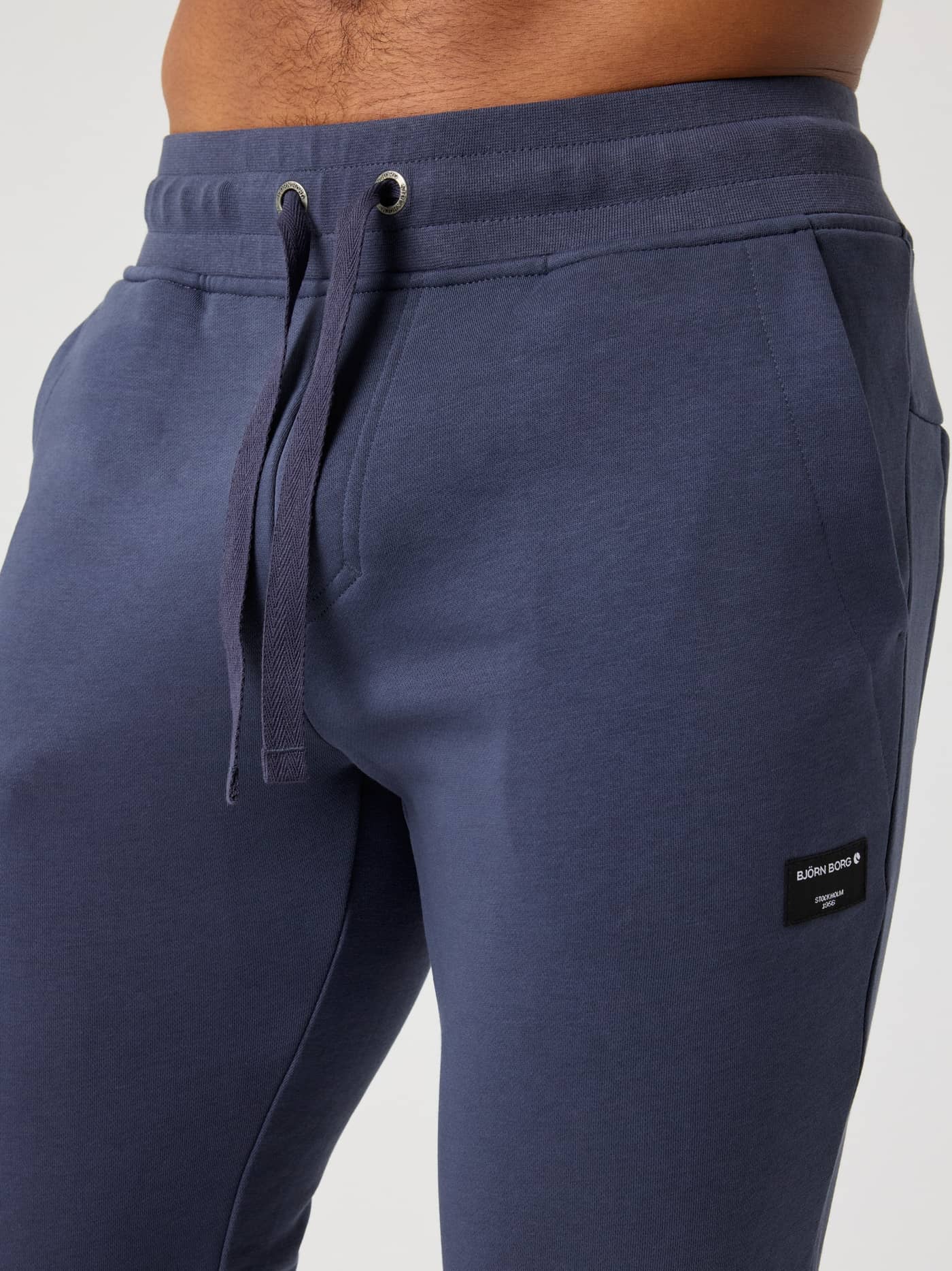 Närbild på Centre Tapered Sweatpants i Odyssey Gray (Blå) med dragsko och en svart logoetikett. - Image 4